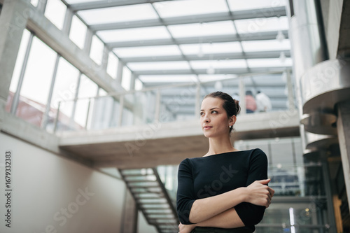 Free Download Portrait of young businesswoman standing in modern openspace office building. - GFXLoad