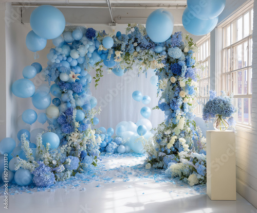 Arco floral con globos azules y blancos, pétalos en el suelo y jarrón decorativo, ideal para bodas, sesiones fotográficas y eventos con estética romántica, elegante y ambientación natural.