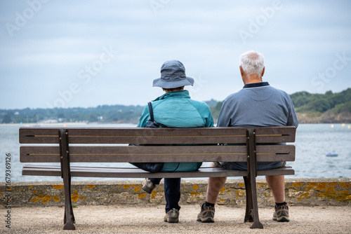 Couple de retraité assis sur un banc face  à la mer en Bretagne. Aout 2025