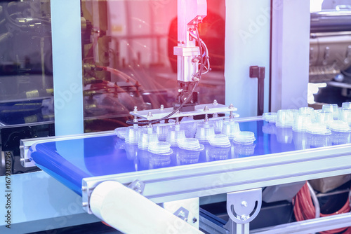 Production line for the production of plastic packaging by injection molding. Small round disposable containers on a conveyor, automation and modern production technologies