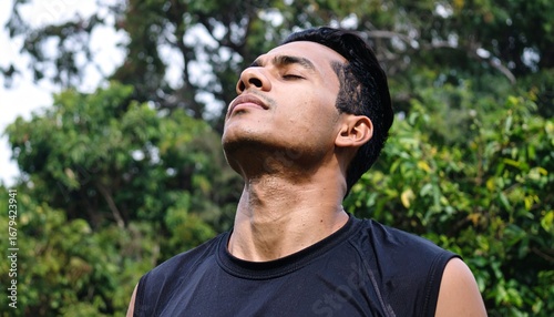 Serene young man practicing mindfulness and deep breathing exercises outdoors, connecting with the tranquility of nature for mental wellness