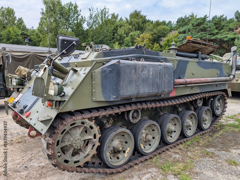 Fototapeta premium Military vehicle parked in a forested area during daytime in an outdoor display setting