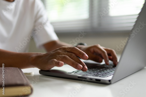 Black man's hands are pressing the keyboard on a laptop.