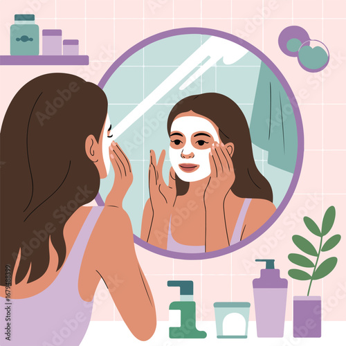 Young woman applying facial mask looking at mirror in bathroom at home