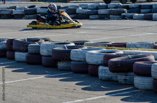 Dynamic Action Shot of Kid Driving Yellow Kart.Child Kart Racer Surrounded by Tire Barriers
