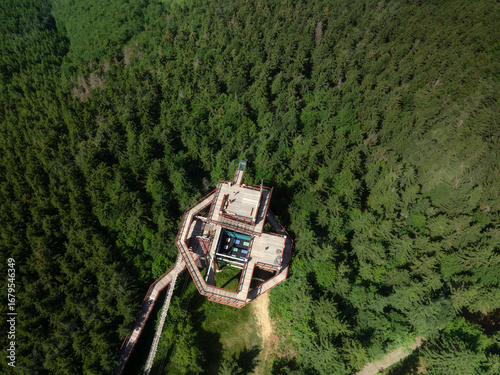 The aerial view of the top of wooden skywalk with glass lookout point surrounded by green lush forest in Pustevny, Beskid Mountains, Czech Republic