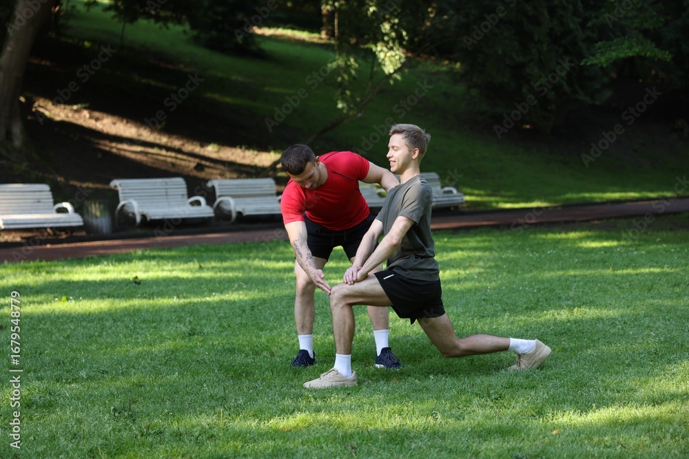 Obraz premium Young man exercising with professional personal trainer outdoors