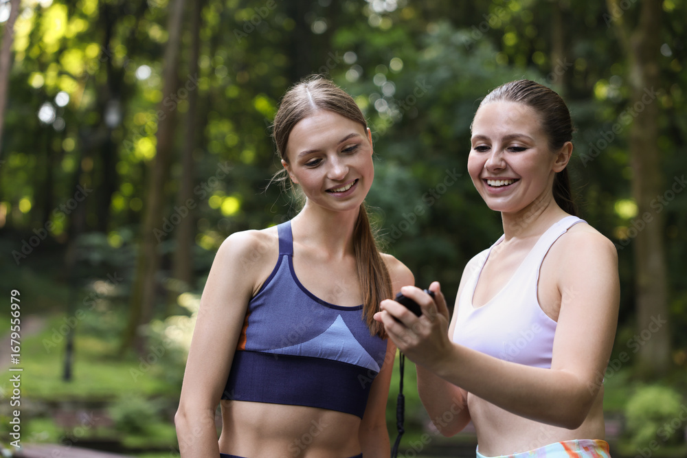 Fototapeta premium Happy young woman with professional personal trainer outdoors