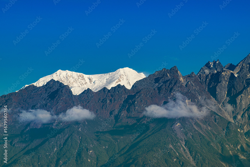Fototapeta premium Beautiful first light from sunrise on Mount Kabru, part of ridge that extends south from third highest mountain in the world Kangchenjunga, Himalayan mountain range, Sikkim, India. Nepal India border.