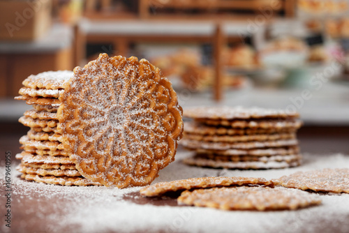 Stacks of Pizzelles on a Bakery Counter Covered in Powdered Sugar