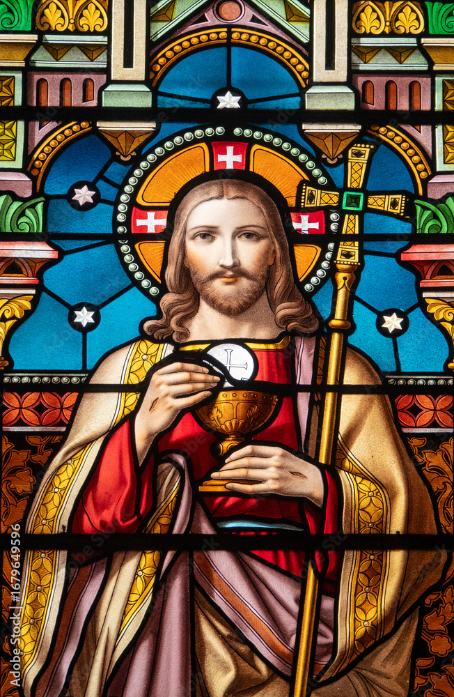 Fototapeta premium Stained glass (1914) of a portrait of Jesus Christ with the Eucharist.