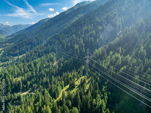 Aerial view of power line pylon in mountaineous area in Switzerland through valley in Canton of Valais.