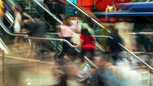 Large crowd of people moving rapidly on an escalator in a vibrant city. Motion blur effect captures the fast pace of urban life, with blurred buses and cars in the background, highlighting constant