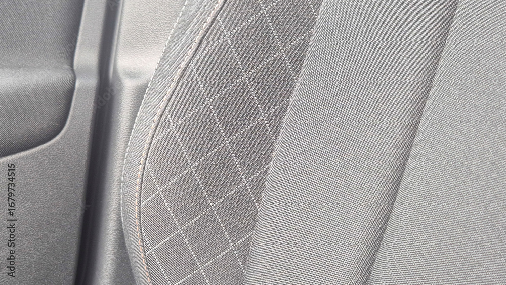 Obraz premium Close-up view of a modern car seat fabric, showcasing an intricate quilted pattern and smooth texture. Ideal for automotive design or upholstery themes.