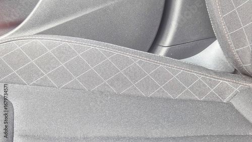 Close-up of a modern car seat interior showcasing gray fabric with diamond stitching patterns. Designed for comfort and style in automotive seating.