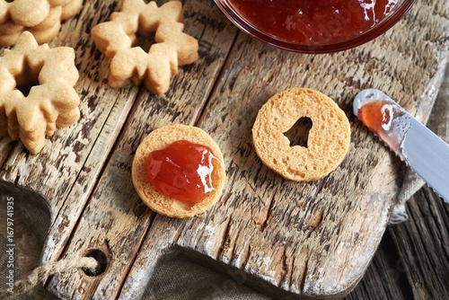 Filling traditonal Linzer Christmas cookies with red strawberry marmalade