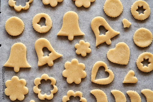 Shapes made of raw pastry dough on baking paper - preparation of Linzer Christmas cookies