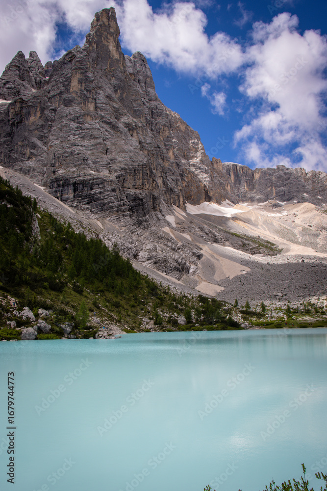 Obraz premium Photography of Lago di Sorapis, Italy, showing the turquoise glacial lake surrounded by Dolomite mountains, pine forests, and dramatic alpine scenery.