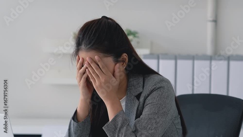 Stressed office woman reading document with worried face and messy paperwork on desk in workplace
