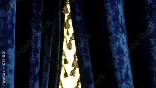 Dark blue velvet curtains, gold tassels, light behind