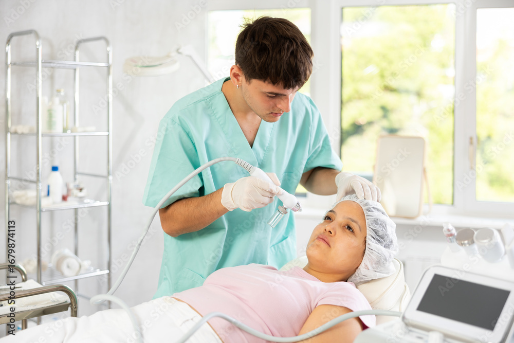 Fototapeta premium Cosmetic doctor confidently uses Hydrogen Oxygen Hydrating attachment to enhance moisture and maintain youthful appearance of client's skin.