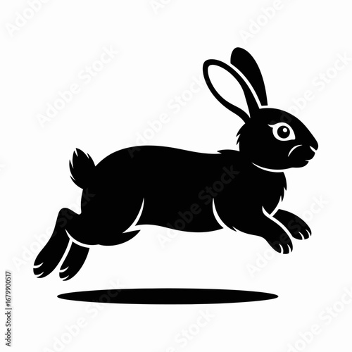 Silhouette of a black rabbit leaping forward with ears perked up