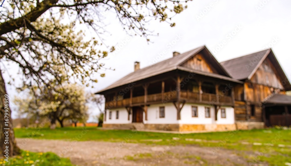 Obraz premium Rustic wooden farmhouse framed by blossoming trees exudes tranquility and timeless charm in a