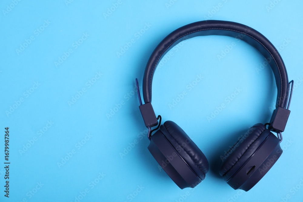 Fototapeta premium Pair of stylish headphones on light blue background, top view. Space for text