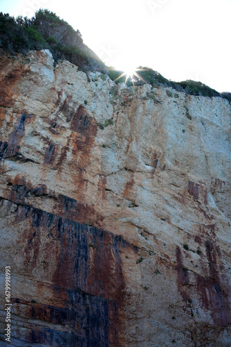Sun is coming out below a massive cliff with sun rays 