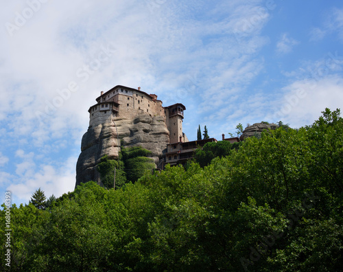 Lone monastery in Meteora, Greece  as seen from below a cliff with wispy clouds