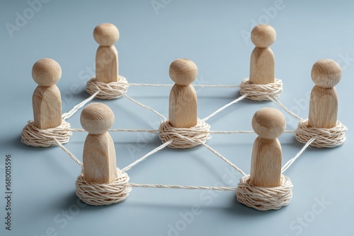  ​Network and Teamwork​ - Group of Wooden Figures Connected by Rope on Light Blue Background, Symbolizing Unity, Community, and Interdependence.