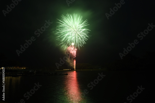 湖面に浮かぶ打ち上げ花火と人の影