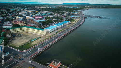 Cityscape with houses, roads, and lush greenery at the foot of the mountains.