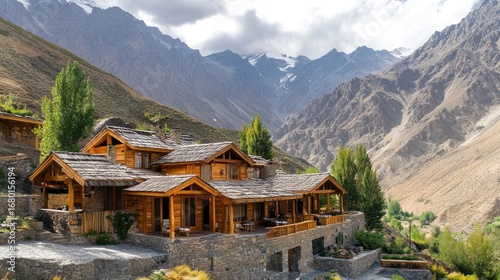 Luxurious wooden lodge nestled in a scenic mountain valley with snow capped peaks under a cloudy sky