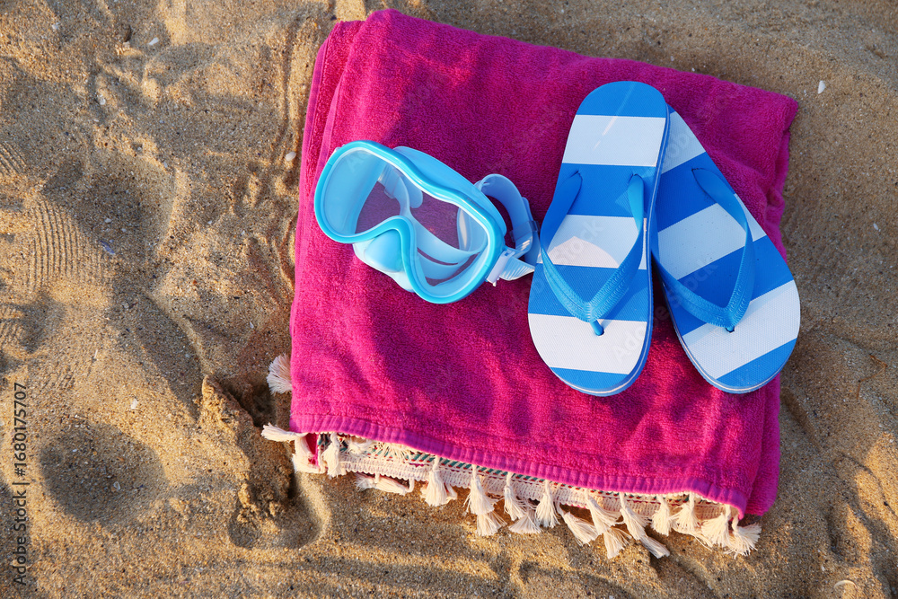 Naklejka premium Snorkeling mask, flip-flops and colorful towel on sea beach