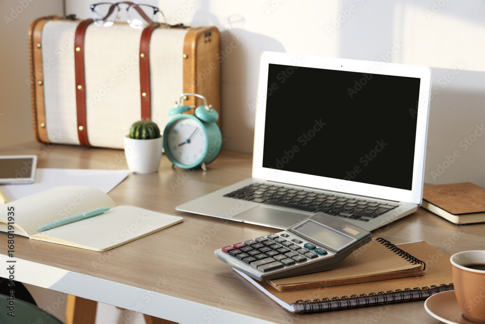 Fototapeta premium Comfortable workplace with calculator, notebooks and modern laptop near white wall