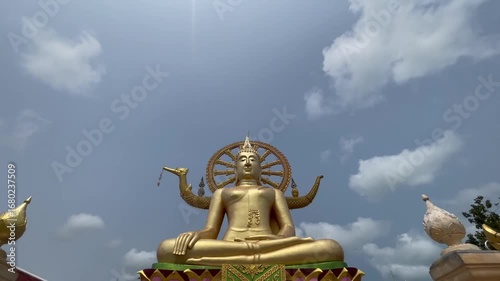 Wallpaper Mural Captivating drone shot of a grand golden Buddha statue with intricate halo and symbolic gestures, ascending stairs, bright sun and blue sky in Ko Samui, Thailand. Torontodigital.ca