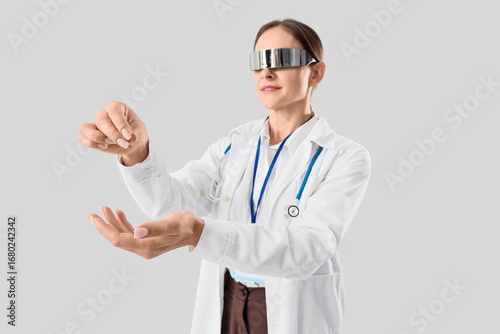 Female doctor in goggles holding something on light background