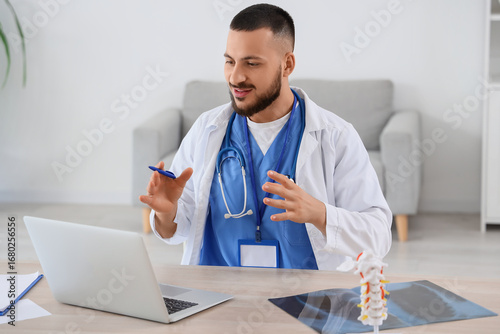 Male doctor with laptop giv...