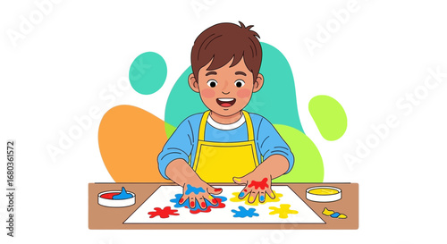 A young boy happily painting with his hands using colorful paints on paper