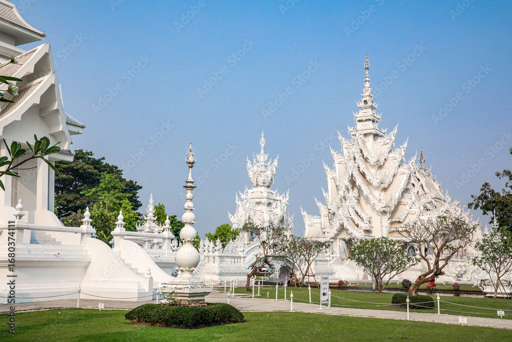 Naklejka premium Wat Rong Khun, or the White Temple, is a Buddhist temple located in Chiang Rai, Thailand. The temple attracts many tourists. The White Temple was built by Chalermchai Kositpipat, who also designed