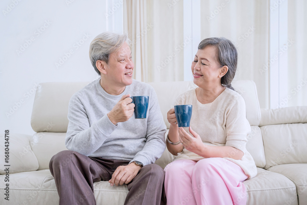 Obraz premium Happy Senior Couple Drinking Coffee and Talking on the Couch