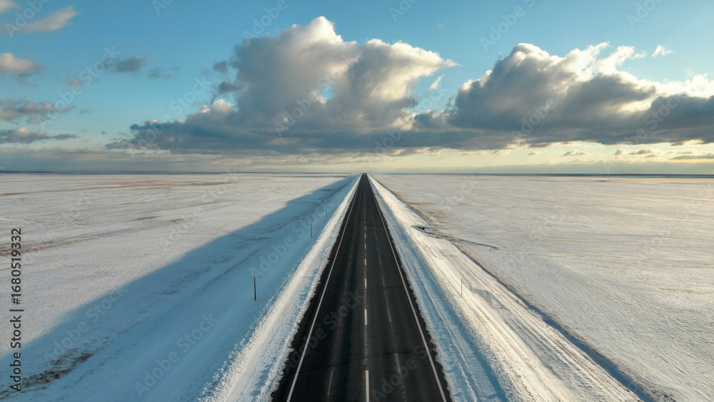 Fototapeta premium Drive through winter wonderland on a stunning asphalt road stretching toward the horizon under a calming sky