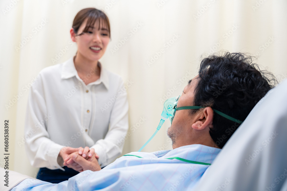 Obraz premium 人工呼吸器をつけた男性と病院に駆けつけた家族