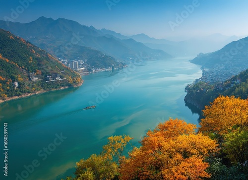Aerial view of River with golden autumn foliage, blue water and misty orange mountains reflected in glass-like lake