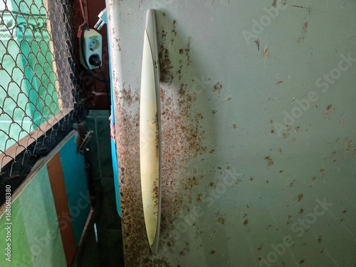 Close-up of old refrigerator handle with rust, dirt, and scratches in worn kitchen setting
