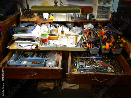 A tinkerer's stacked and cluttered workbench