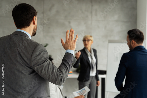 Business lecture with a male participant raising his hand to answer a question
