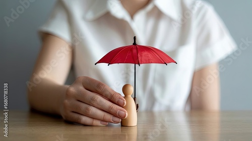 Insurance Concept: A metaphorical representation of protection, security, and safeguarding against unforeseen risks. A miniature figure stands under a vibrant red umbrella, held by a person.