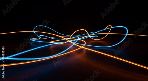Blue and orange glowing light trails on a dark surface with a black backdrop
